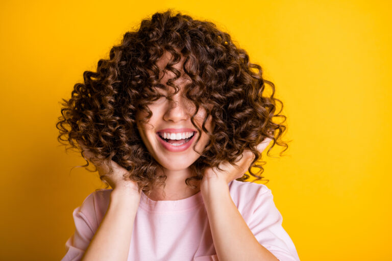 Photo portrait of girl with curly hairstyle wearing t-shirt laughing touching hair isolated on bright yellow color background